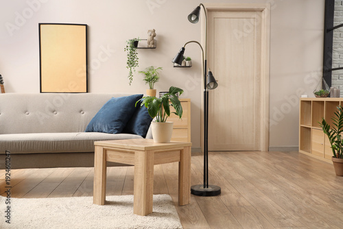 Interior of light living room with grey sofa, table and lamp