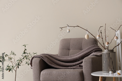 Vase with tree branches and Easter eggs in modern living room