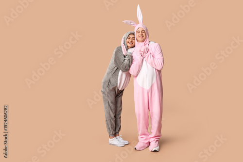 Obraz na plátně Beautiful young couple in bunny costume on brown background