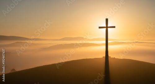 Large Christian cross silhouette on a hill at sunrise with golde