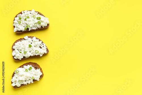 Tasty sandwiches with cottage cheese on yellow background