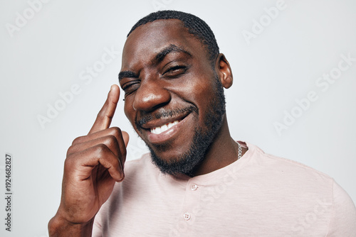 Canvastavla African American man with dark skin smiling and pointing finger to head in casual shirt on white background