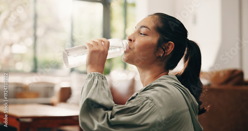 Photos Woman, relax or drinking water in living room with bottle, wellness or natural detox for gut health