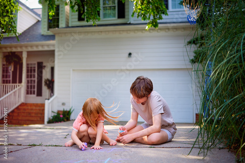 Wallpaper Mural Brother and Little Sister Playing Tic Tac Toe Game with Chalk on Driveway — Happy Sibling Bonding and Outdoor Childhood Play at Home in Suburban Neighborhood Torontodigital.ca