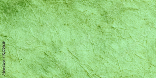 Green crumpled paper texture background with wrinkled parchment effect shows intricate folds, creases, and shadows effect suitable for vibrant graphic design.