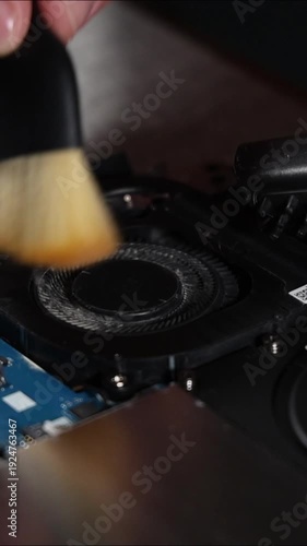 Careful cleaning of laptop cooling fan with brush and screwdriver close up repair process