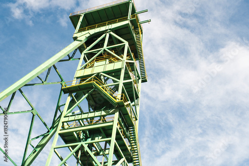 Old green mining tower with the sky in the background.