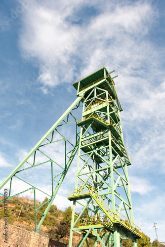 Old green mining tower with the sky in the background.