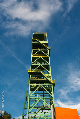 Old green mining tower with the sky in the background.