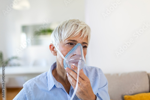 Foto Senior woman using an oxygen mask for respiratory therapy at home
