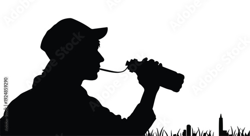 Silhouette of a person in a cap drinking from a water bottle on a bright day.