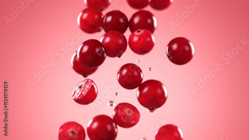 Vibrant red cranberries splashing and falling with water droplets against a soft pink background, showcasing their freshness and juicy texture, perfect for healthy eating concepts