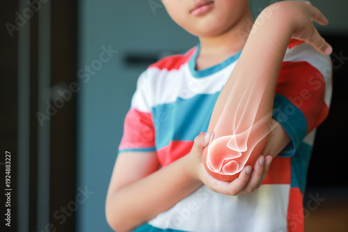Quadro em tela Little boy suffering from elbow joint pain with red x-ray bone graphic overlay, child touching arm feeling ache from injury, inflammation, fracture or accidental fall while playing at home