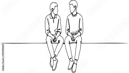 Two young men sitting together, talking and looking at each other.