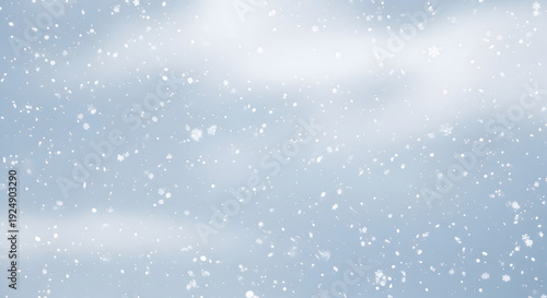 Snowflakes falling gently against soft blue sky background