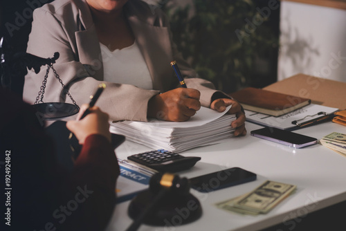 Judge gavel with Justice lawyers having team meeting at law firm in background. Notary with client in office