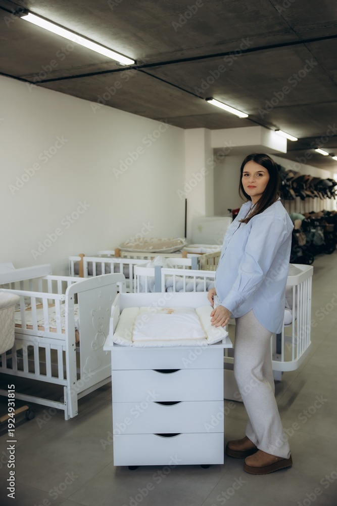 Obraz premium Pregnant woman checking changing table in baby shop