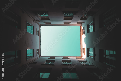 Photography Looking straight up through a dark narrow courtyard, tall apartment walls frame