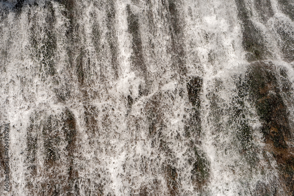 Fototapeta premium Detailed texture of cascading waterfall against rocky cliff