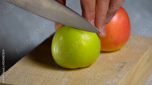 Cutting a red apple with a knife on an authentic wooden board