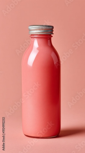 Smooth pink smoothie drink in a glass bottle on a pastel coral background, highlighting freshness and health
