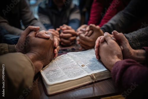 Hands clasped in prayer around an open book, diverse group close together