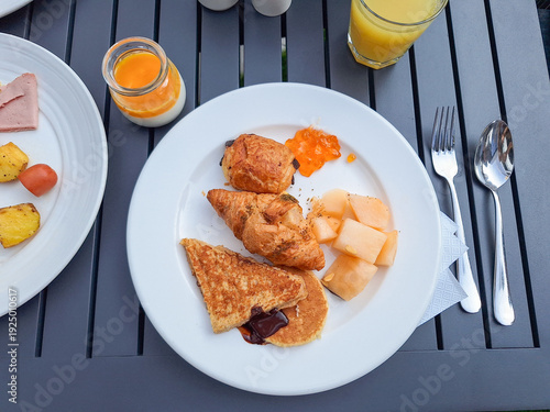 Breakfast: plates of food, orange juice, yogurt,  bakery products on table. Top view