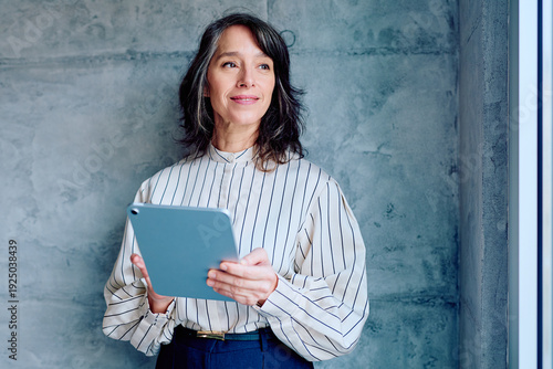 Fotografi Experienced professional woman with grey hair holding a digital tablet