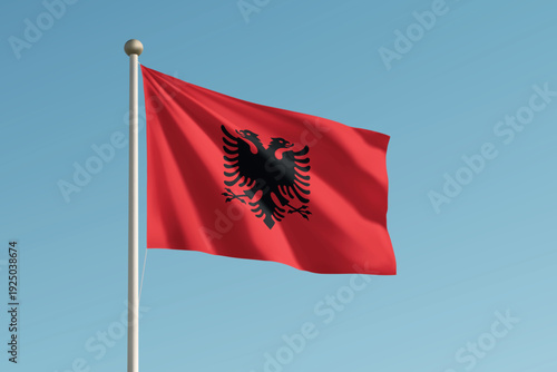 Albania national flag waving on pole against clear blue sky background.