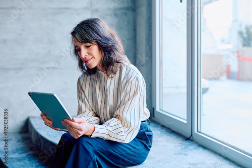 Fotografía Woman sitting on steps using a digital tablet for work or communication, reflect