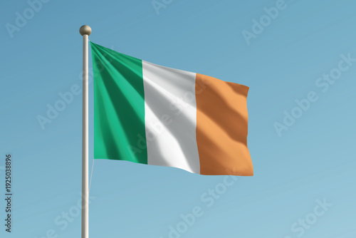 Ireland national flag waving on pole against clear blue sky background.