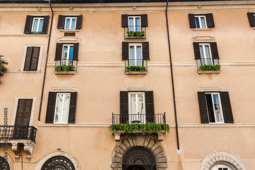 Obraz premium Traditional residential building facade with balconies and shutters in rome italy