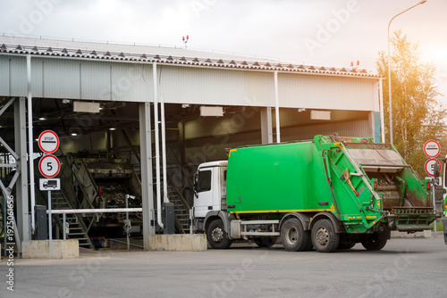 Quadro su tela Bright green refuse truck waits at the entrance gate of a large waste processing facility