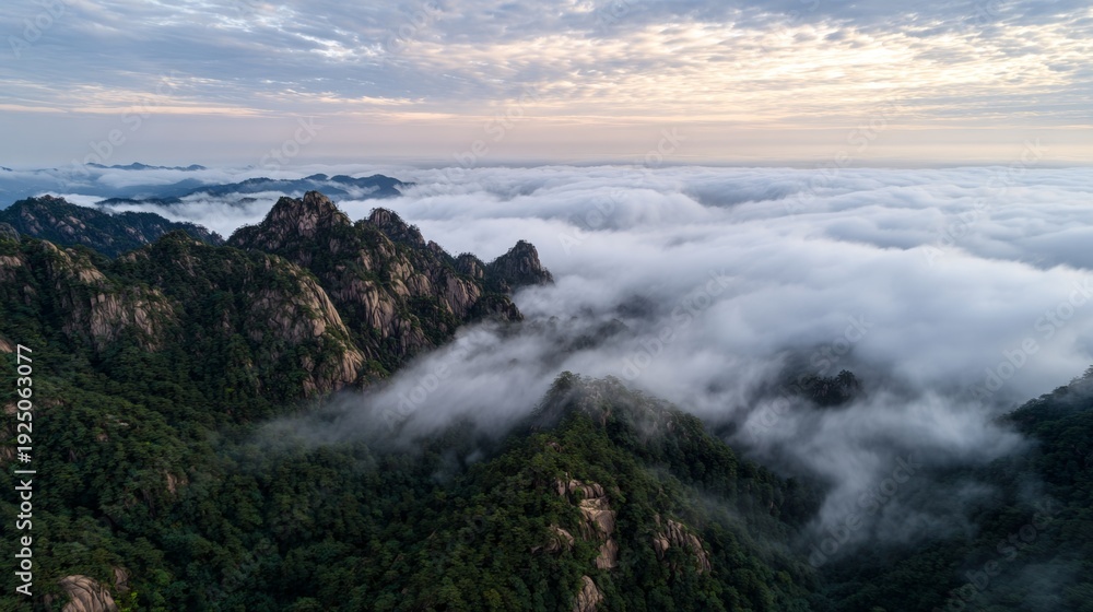 Obraz premium Mountain peaks emerging above sea of clouds at sunrise