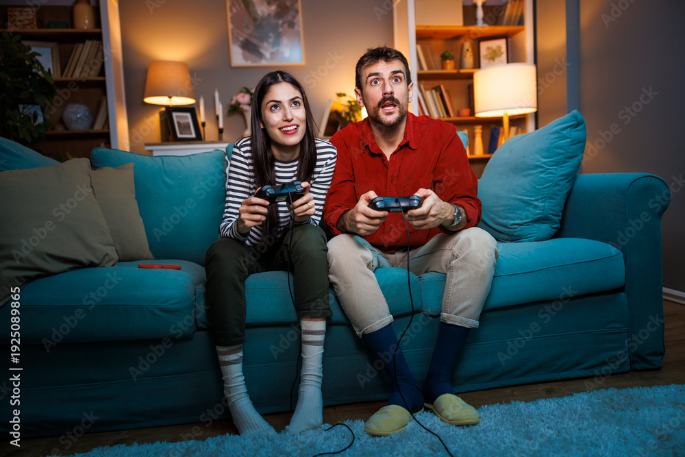 Obraz premium Couple having fun playing video games at home at night
