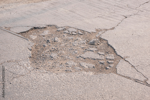 The old badly damaged street background with broken texture and pothole on concrete road surface