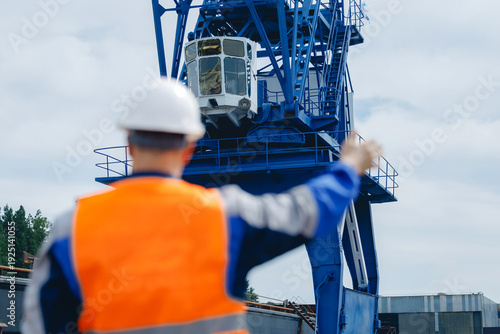 Foto Male worker at shipyard directing cargo crane in industrial port setting