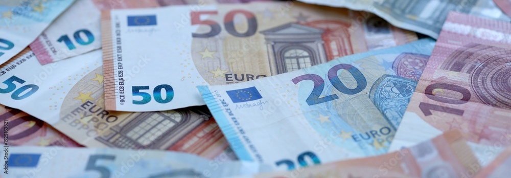 Obraz premium Euro money bills pile on table. Eurozone banknotes of EUR currency close up.