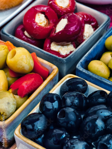 Different types of olives and stuffed peppers served in small bowls on a table during a meal or gathering