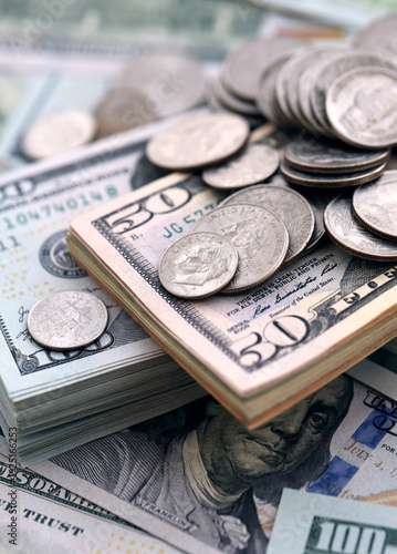 Big amount of United States coins on hundred and fifty dollar money bill wads on table