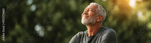 Senior man outdoor sunlight relaxation wellness meditation peaceful portrait, gray hair and beard, eyes closed, breathing deep, enjoying warm evening light in nature