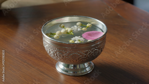 Close up of Thai silver bowl with jasmine and rose petals for Songkran festival ceremony on wooden surface
