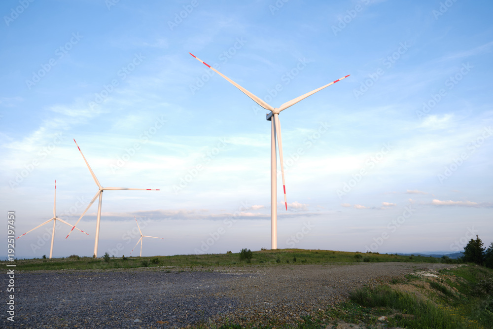 Fototapeta premium Wind Turbines on Hilltop Against Blue Sky