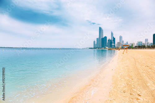 Sandy beach meeting turquoise water, showcasing the modern architecture and skyscrapers of the city along the coastline