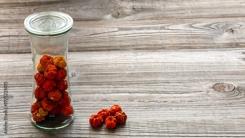 Dry Ethiopian eggplants in a glass jar. Rustic wooden background with copy space.