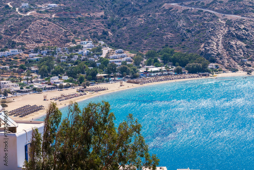 Panoramic view of the popular sandy Mylopotas beach in Ios Greece and various bars with sun umbrellas and sun beds on a windy day