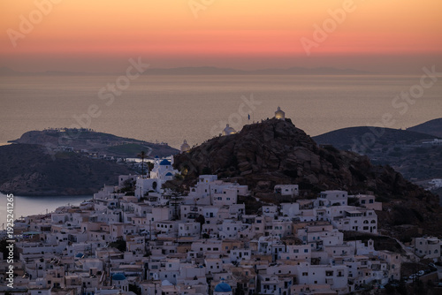 Panoramic view of the beautiful whitewashed village also known as chora, in Ios Greece, and a spectacular orange sunset in the background
