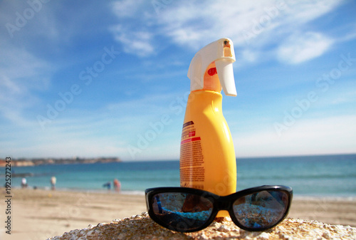 Fotografie Playa, crema protectora y gafas de sol junto al mar en verano de vacaciones