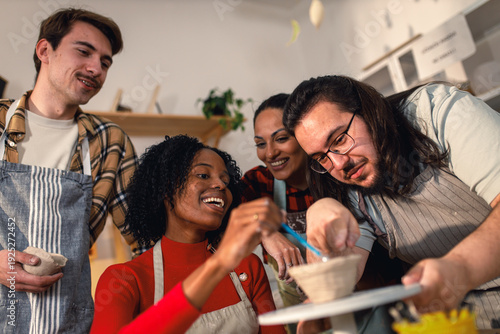Diverse group of friends attending pottery class havng fun making clay objects together.