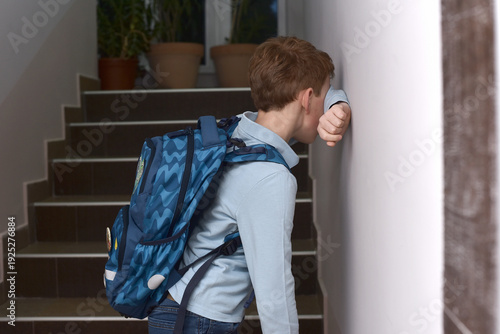 Lonely child leaning against wall with school backpack, expressing fear, anxiety and school problems, concept of emotional struggle, depression and difficult school day
